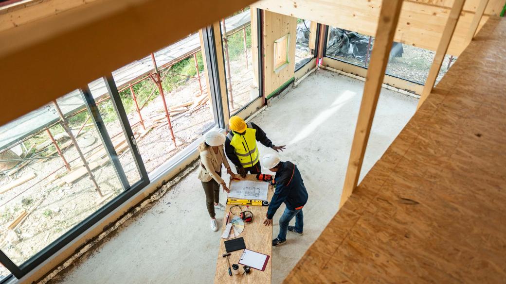 Team of one female architect and two male construction workers on a commercial construction site.