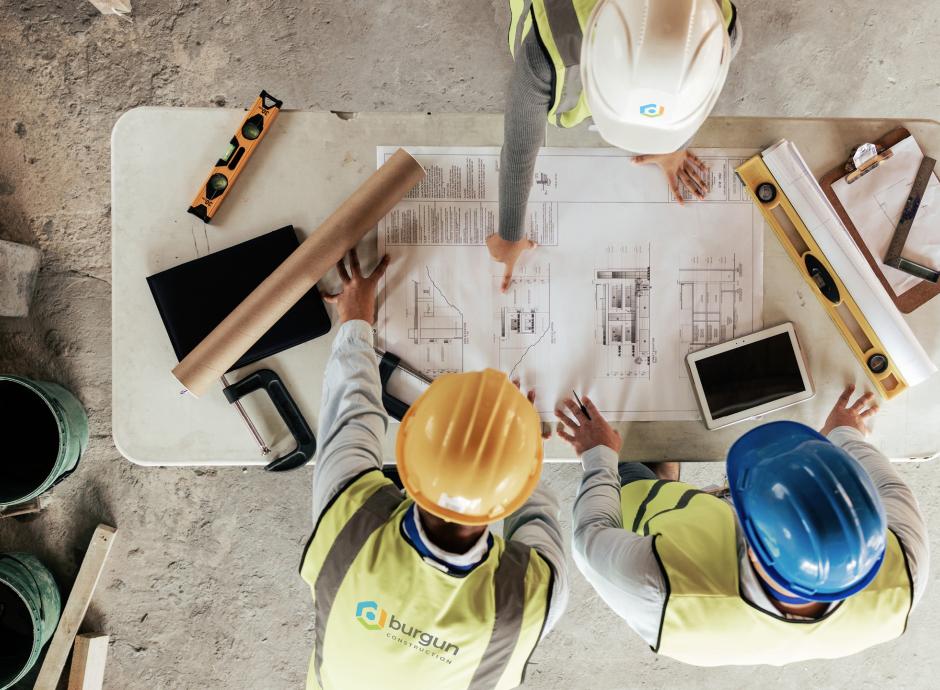 building contractors on building site with plans overhead