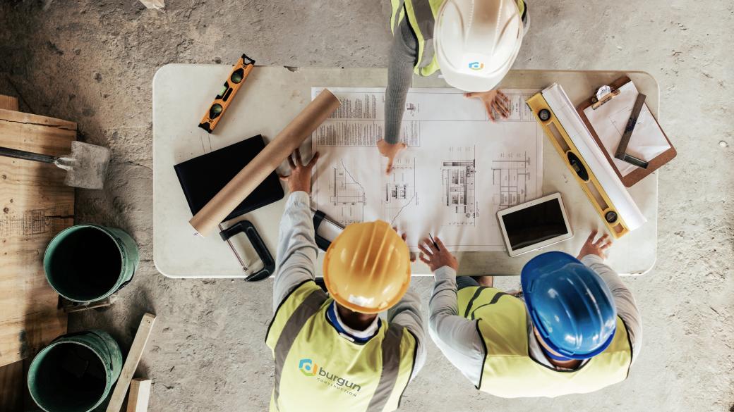 building contractors on building site with plans overhead